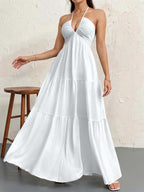 A white textured maxi dress with a plunging halter neckline and a tiered, flowing skirt.