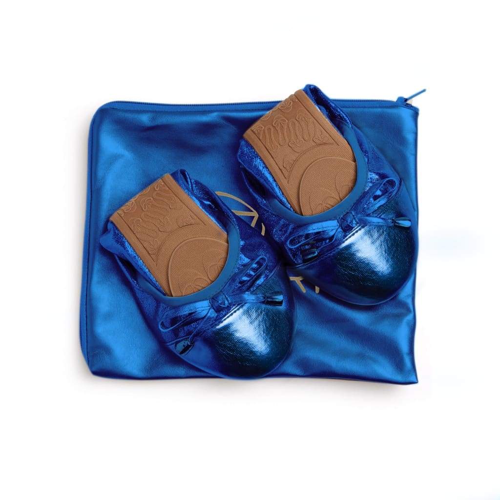 Pair of cobalt blue metallic foldable ballet flats with bow detail, resting on a matching blue zip travel pouch.
