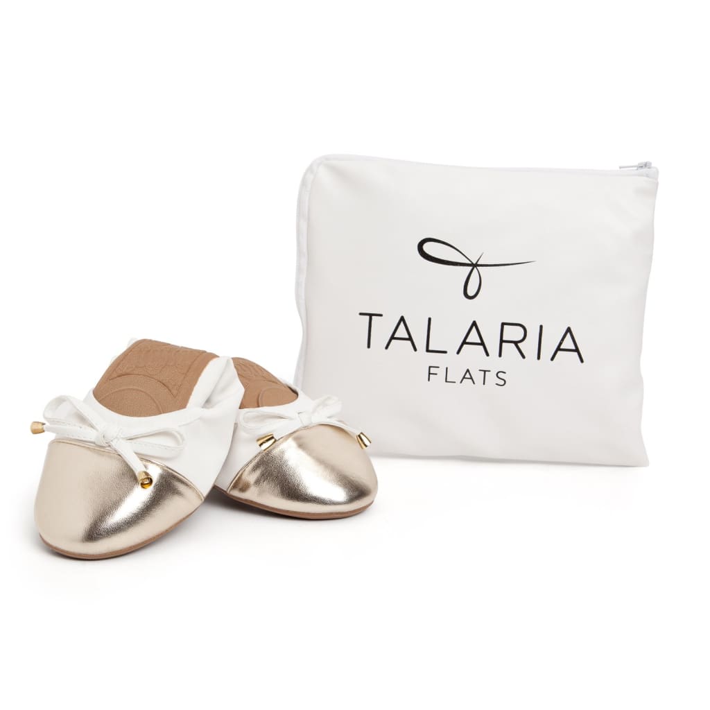 Premium white and gold ballet flats with a bow detail, set next to a white Talaria Flats branded pouch.