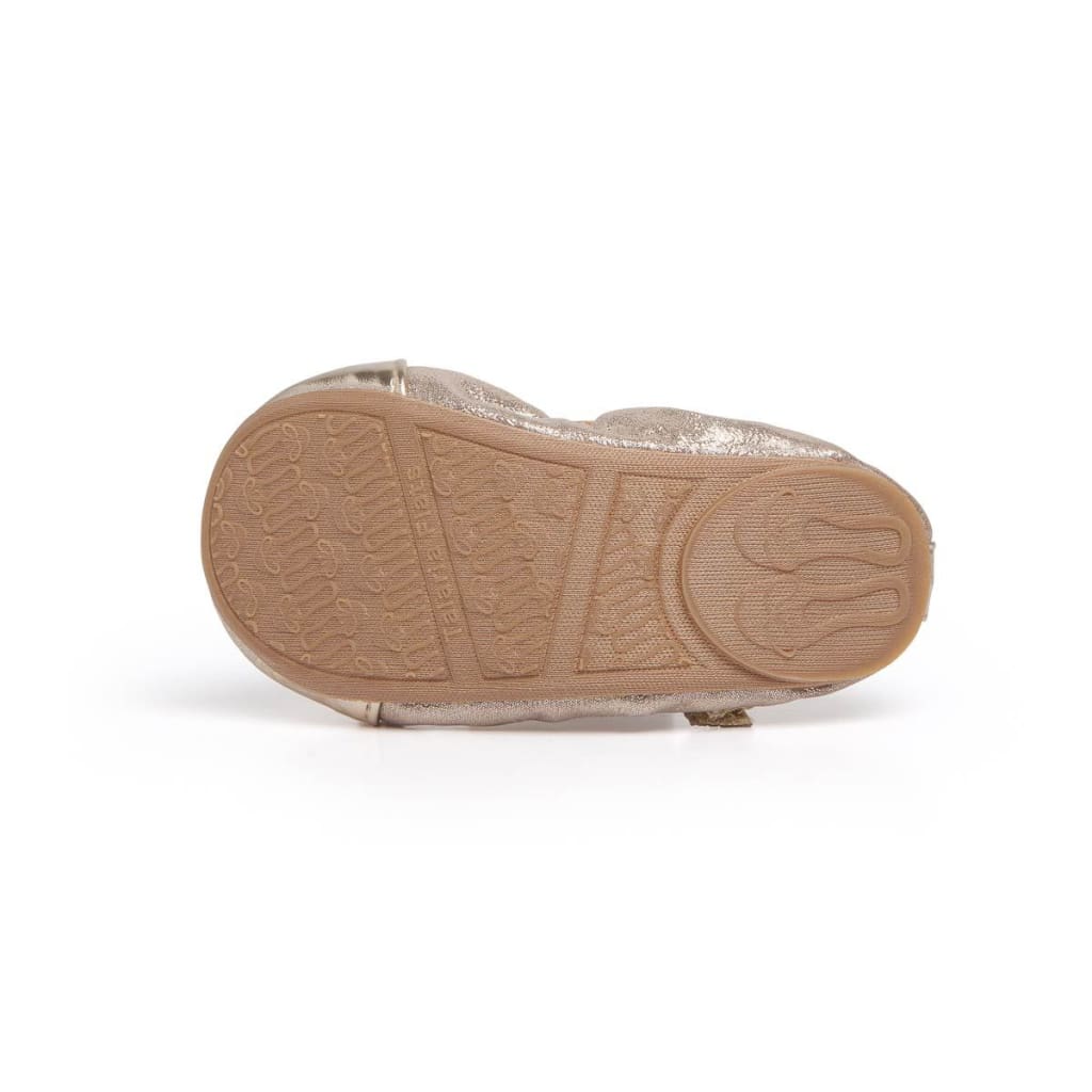 Underside of a metallic gold Talaria Littles flat, showing the patterned rubber sole and textured shoe exterior.